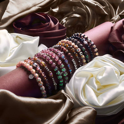 NOGU November’s Color Palette features stacked beaded bracelets in mocha bronze, blush, black and jewel tones on satin drapery.