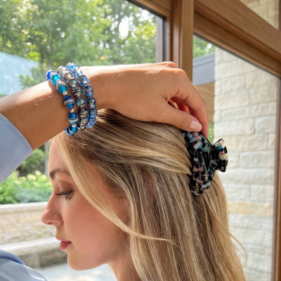 NOGU Sapphire Solstice handcrafted blue and silver beaded bracelets styled with a patterned claw clip in sunlit hair.
