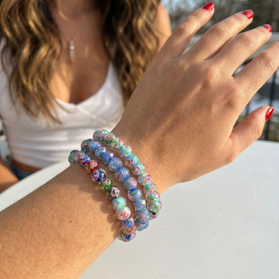 NOGU Made to Pair Wildflowers Firefly Glass bracelets layered on a wrist, with pastel blue, green and pink floral glass beads.