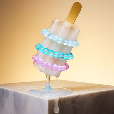 NOGU End of Summer stackable beaded bracelets in iridescent white, aqua blue, and pink on a melting popsicle.