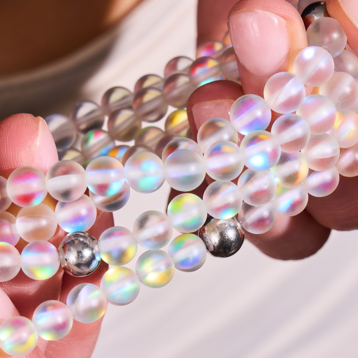NOGU iridescent frosted bead bracelet with translucent rainbow glass-like beads and polished silver-tone accents.