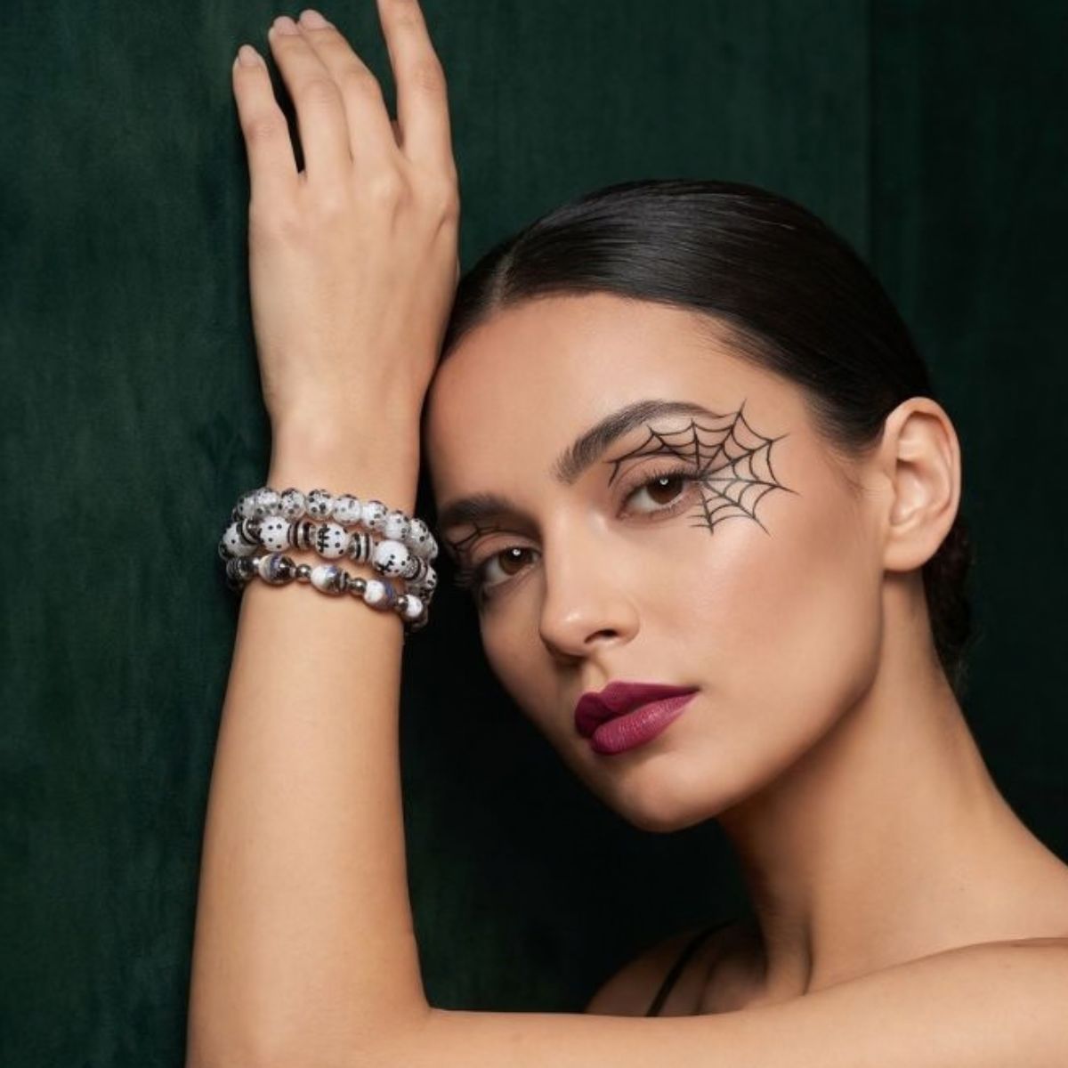 NOGU stacked silver-tone and white beaded stretch bracelets with skull and evil eye motifs, styled for Halloween.