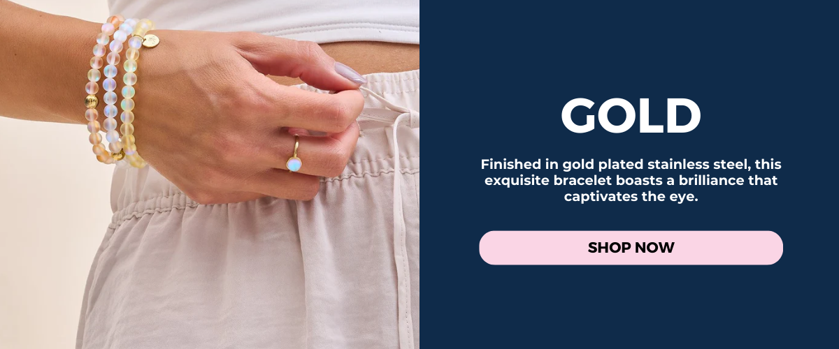 Stacked gold-plated stainless steel bracelets with iridescent pastel beads, worn with a delicate turquoise charm ring.
