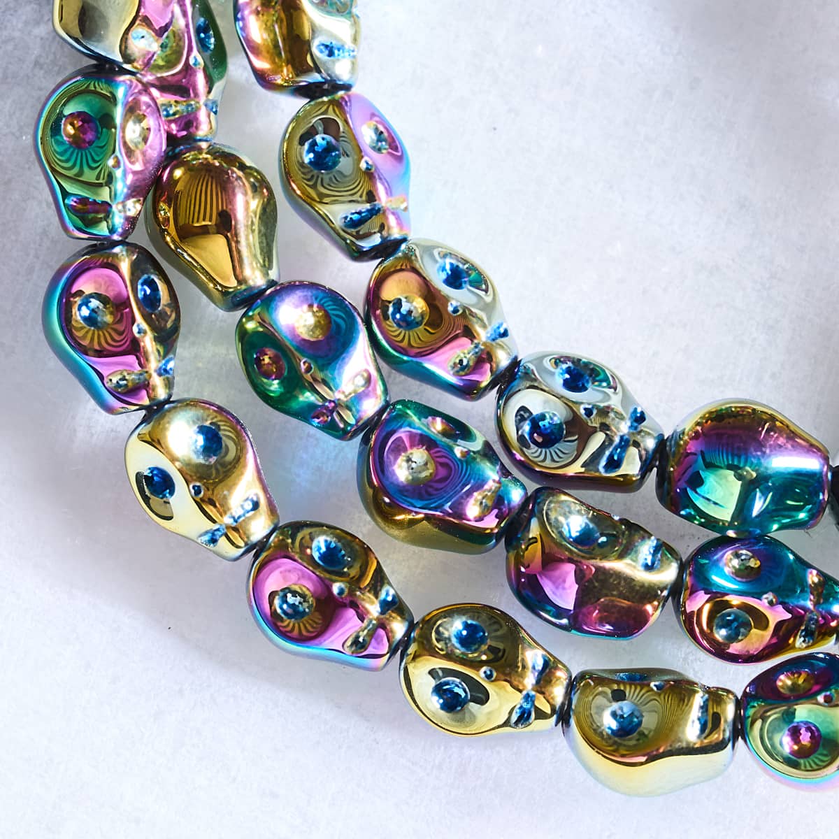 NOGU iridescent skull bead bracelet with glossy rainbow metallic finish and sparkling blue crystal eyes.