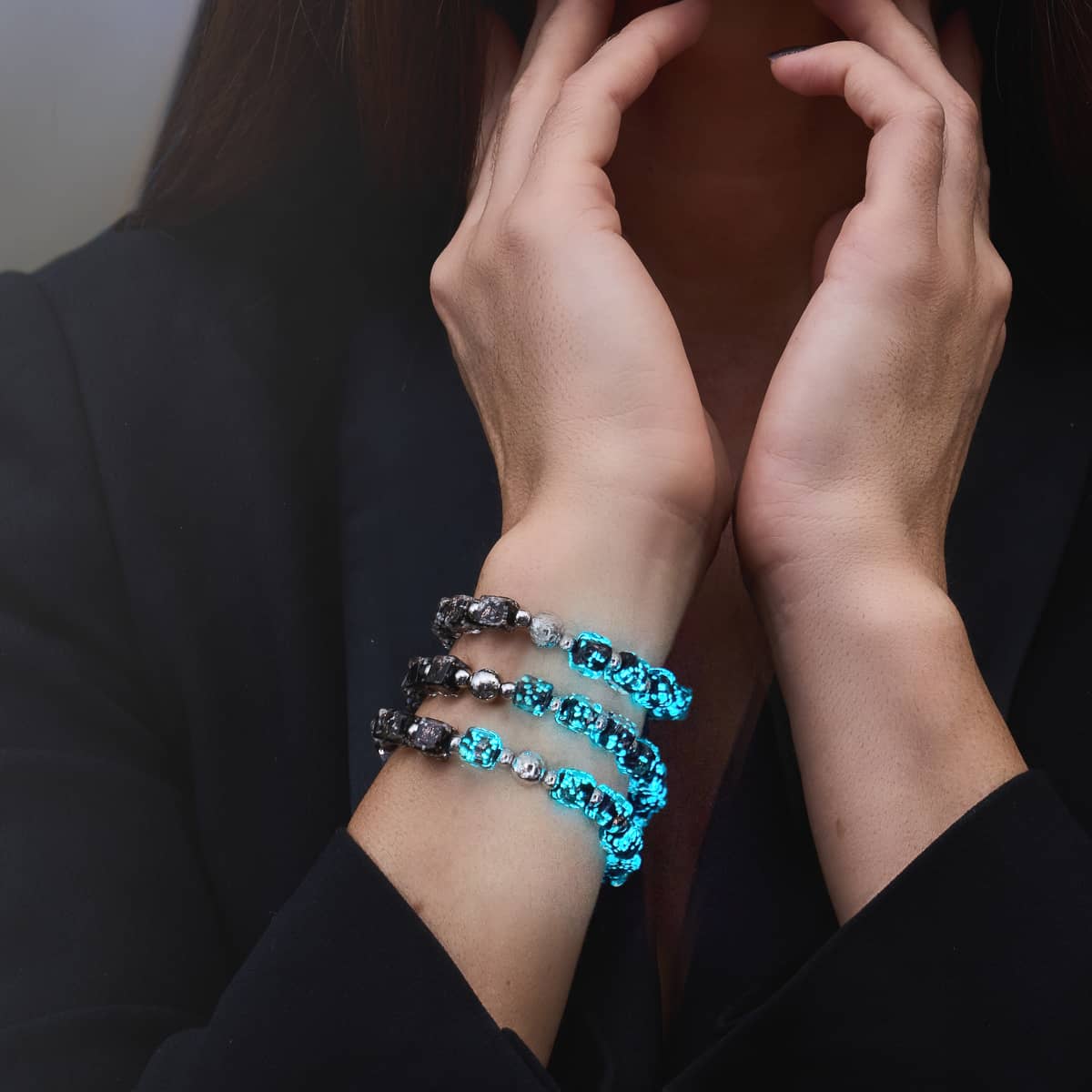 Stacked turquoise-blue crystal and silver bead stretch bracelets worn at the wrist with a black blazer.