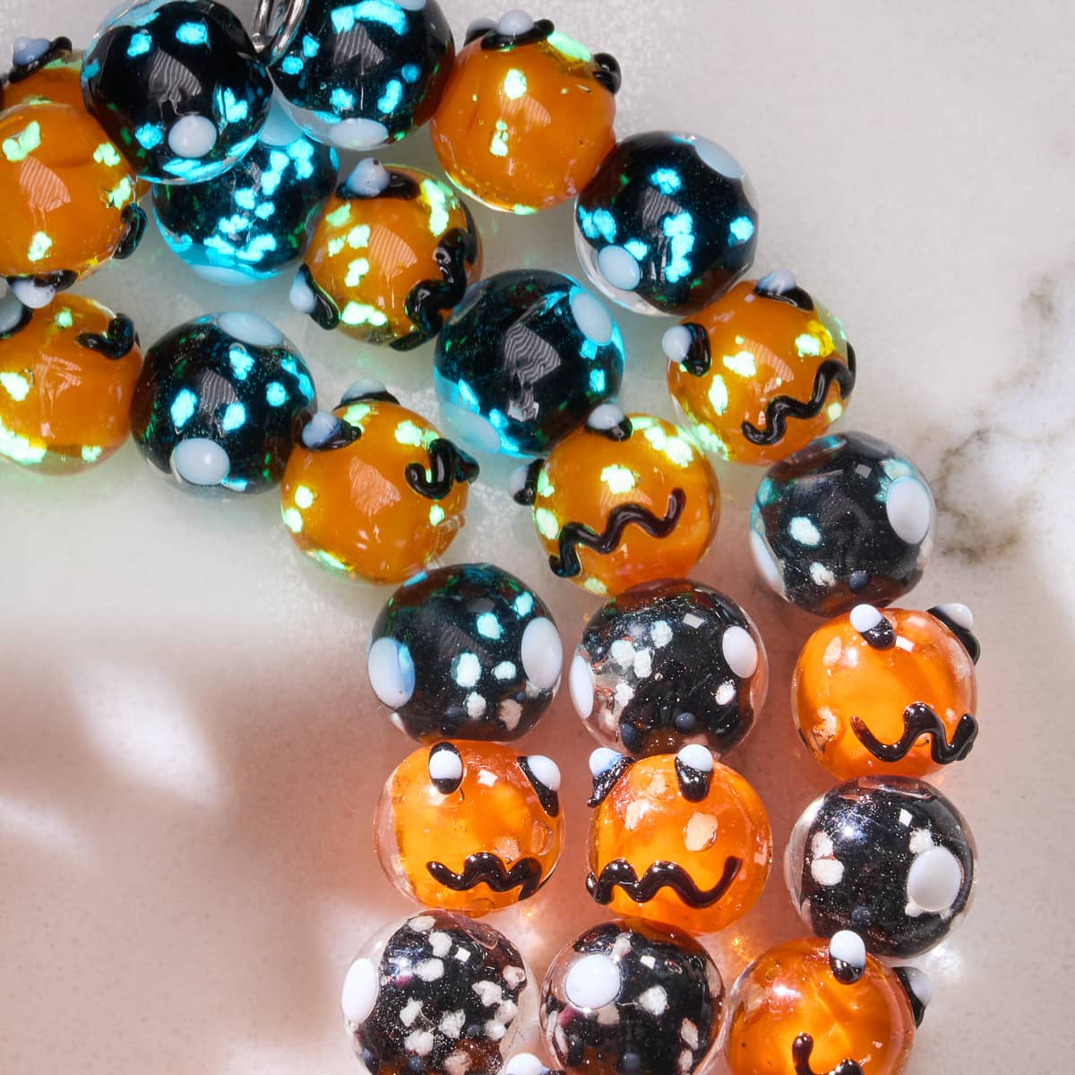 Midnight Pumpkin bracelet close-up showing orange and black Firefly Glass beads with glowing accents on silver base by NOGU