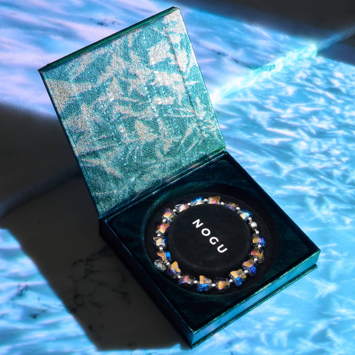 Unicorn Blue silver butterfly bracelet with stretch elastic cord in a teal textured NOGU presentation box