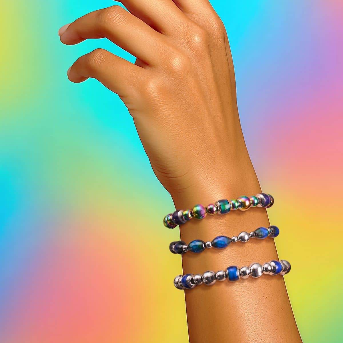 Stacked NOGU beaded bracelets with silver-tone metal and iridescent blue, green and purple beads on a wrist.