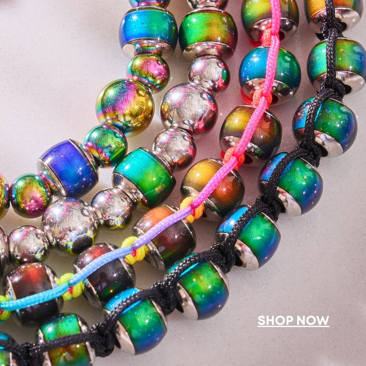 NOGU Pool Party beaded bracelets with iridescent rainbow glass beads, silver-toned spacers, and colorful cord details.