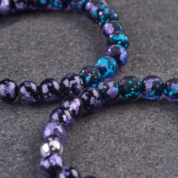Violet Eclipse lunar glass bead bracelet with glossy black beads flecked in vibrant purple and turquoise blue.