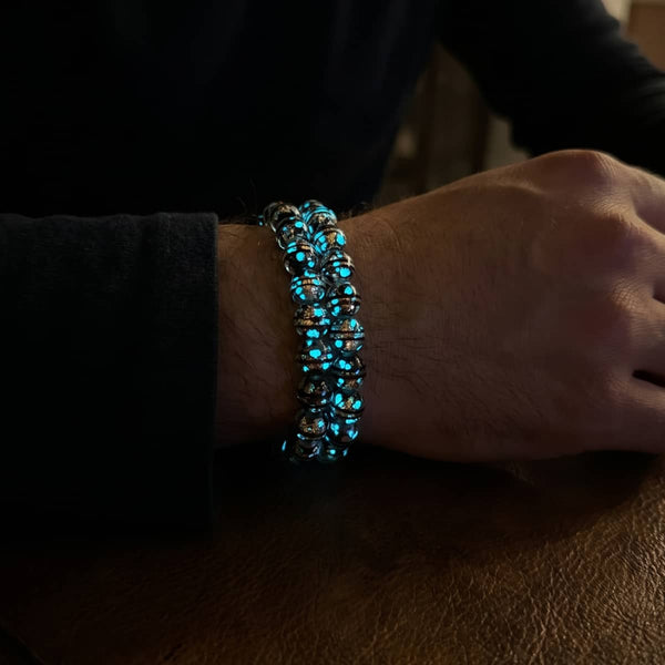 Volcanic Ember Firework Glass Orbit bracelet with silver-tone beads glowing bright blue on a wrist.