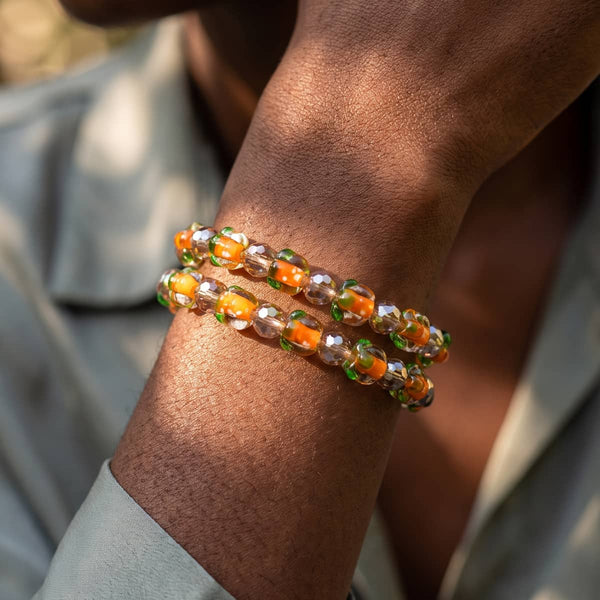 Harvest Moon Prisma Pumpkin Bracelet with orange pumpkin beads, green accents, and faceted silver-toned beads on clear stretch cord.
