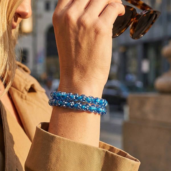 Topaz Flame .925 sterling silver bracelet with round blue Firefly Glass beads, shown stacked on a wrist.
