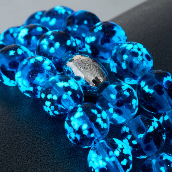 Topaz Flame bracelet featuring blue and white speckled glowing Firefly Glass beads with engraved .925 sterling silver clasp by NOGU