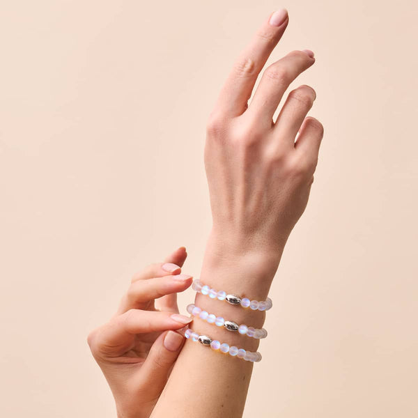 Rainbow White mermaid glass bead bracelets with iridescent 6mm beads and sterling silver charms worn on wrist by NOGU